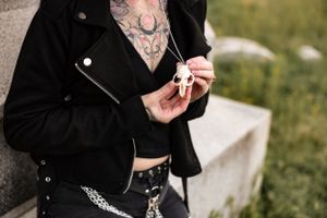 Close-up of tattooed torso in black leather jacket against natural background.