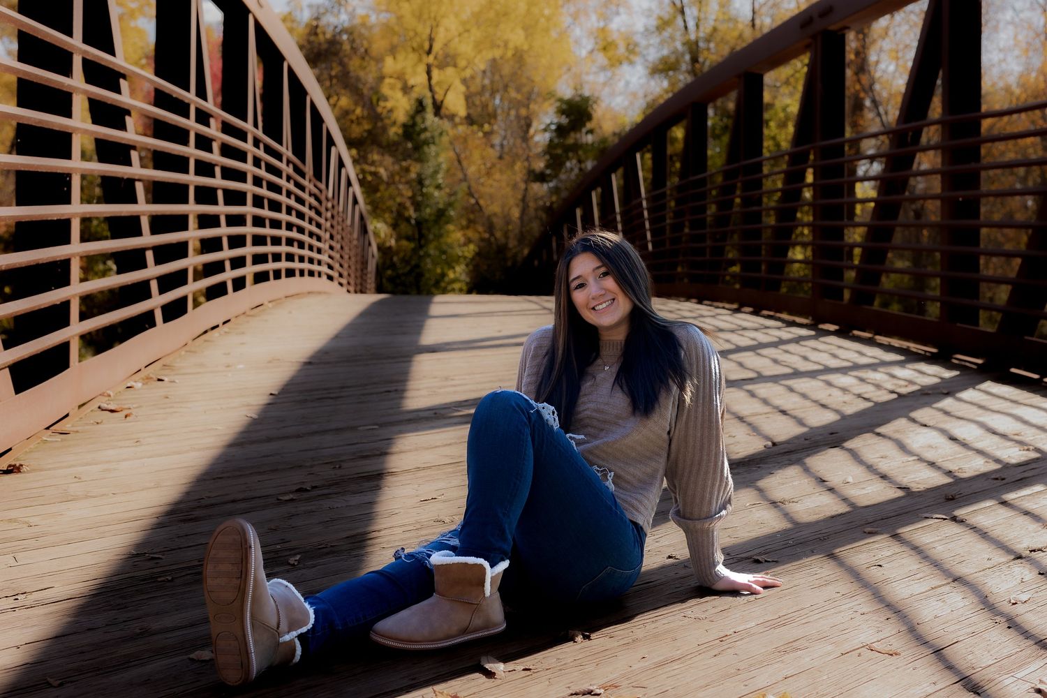 Friends lounging on a wooden bridge during a sunny autumn day.