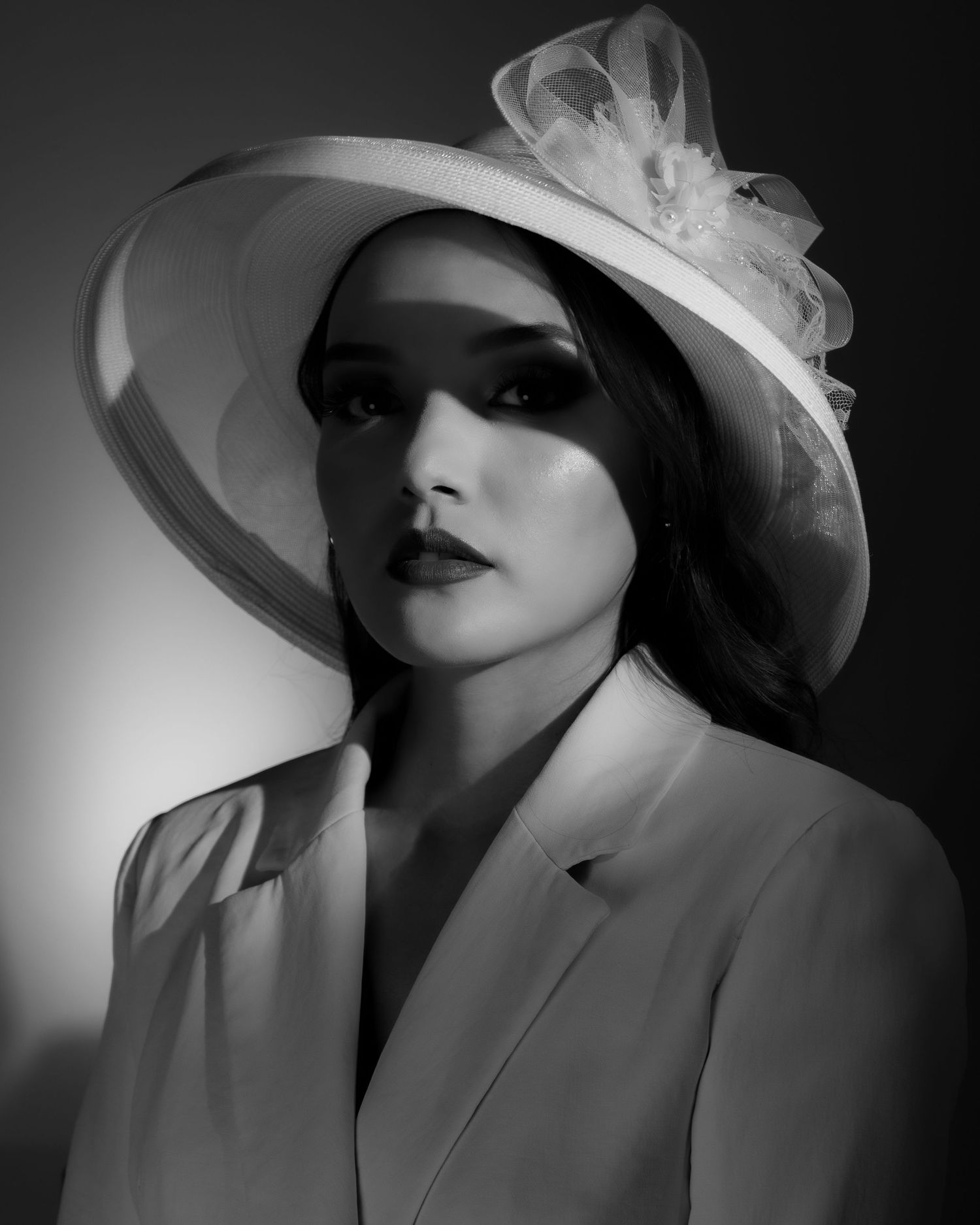 Gabriela Leal. Dramatic black and white portrait featuring an elegant wide-brimmed hat and white blazer.