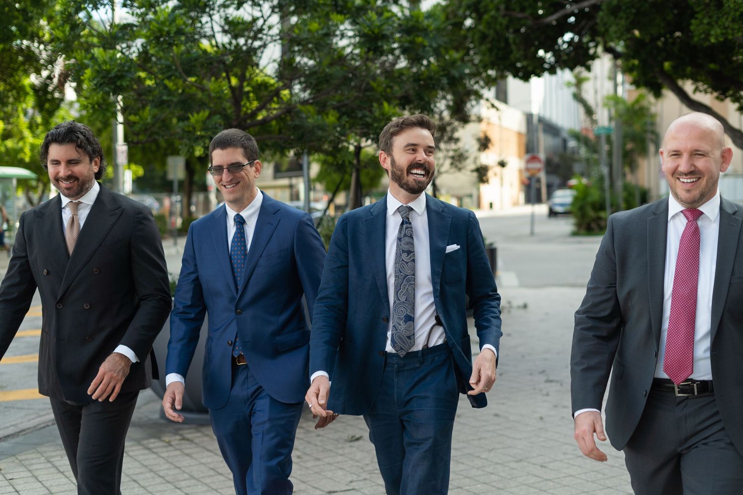 Business professionals walking together on urban sidewalk in suits.