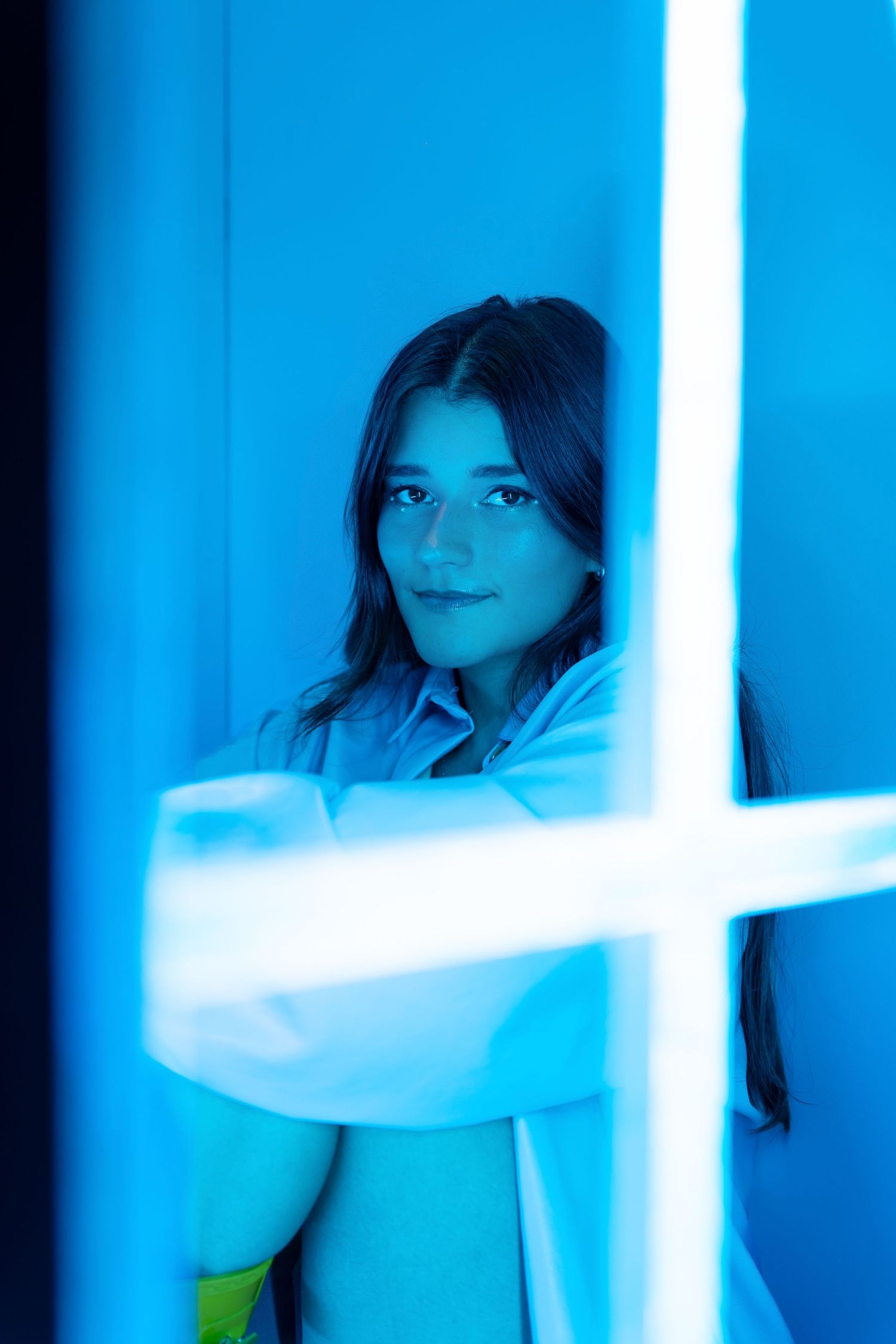 Sarah Sanchez. Sasainforma. Artistic portrait in blue lighting shows person framed by geometric white lines.