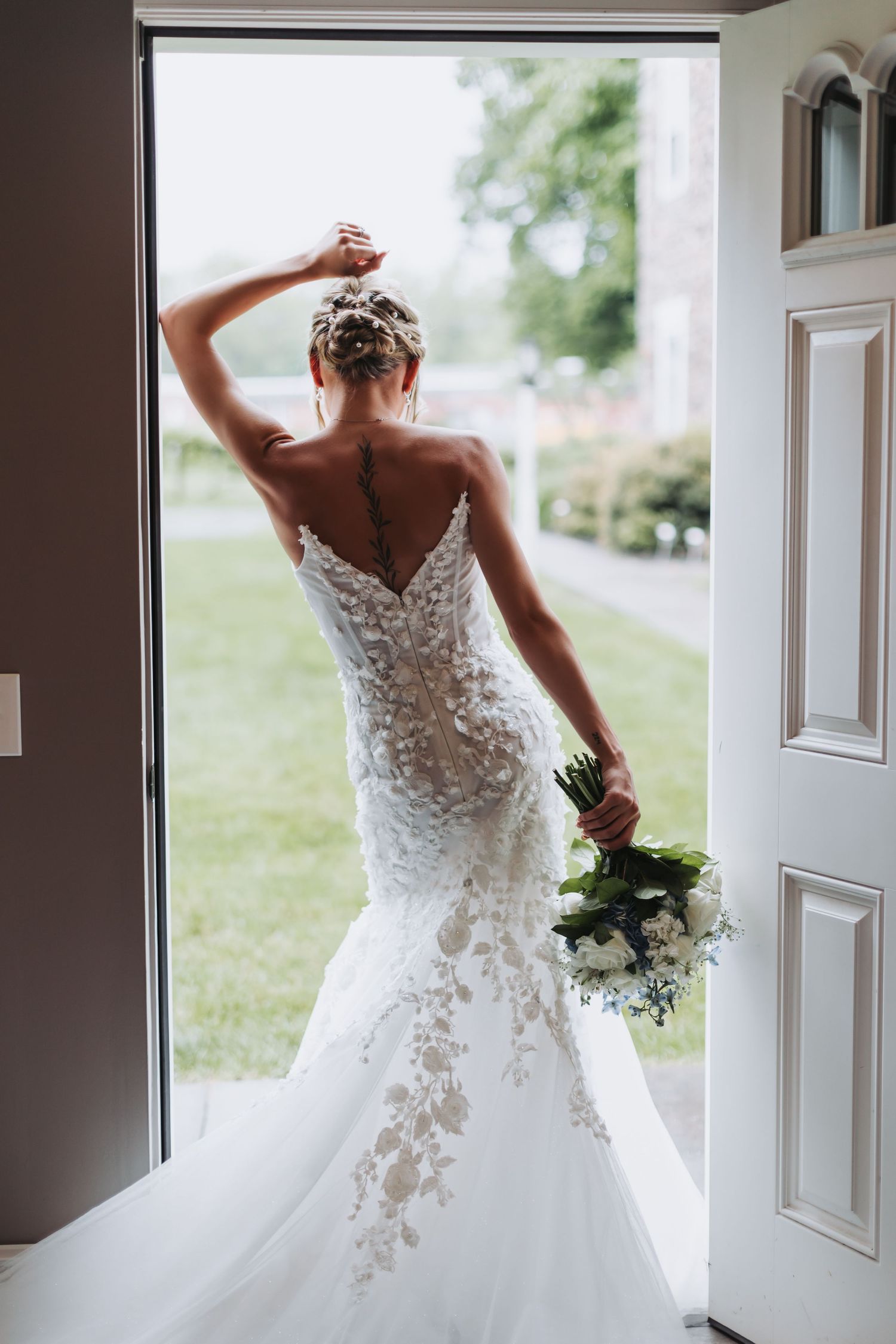 Elegant lace wedding dress with dramatic train silhouetted in doorway.