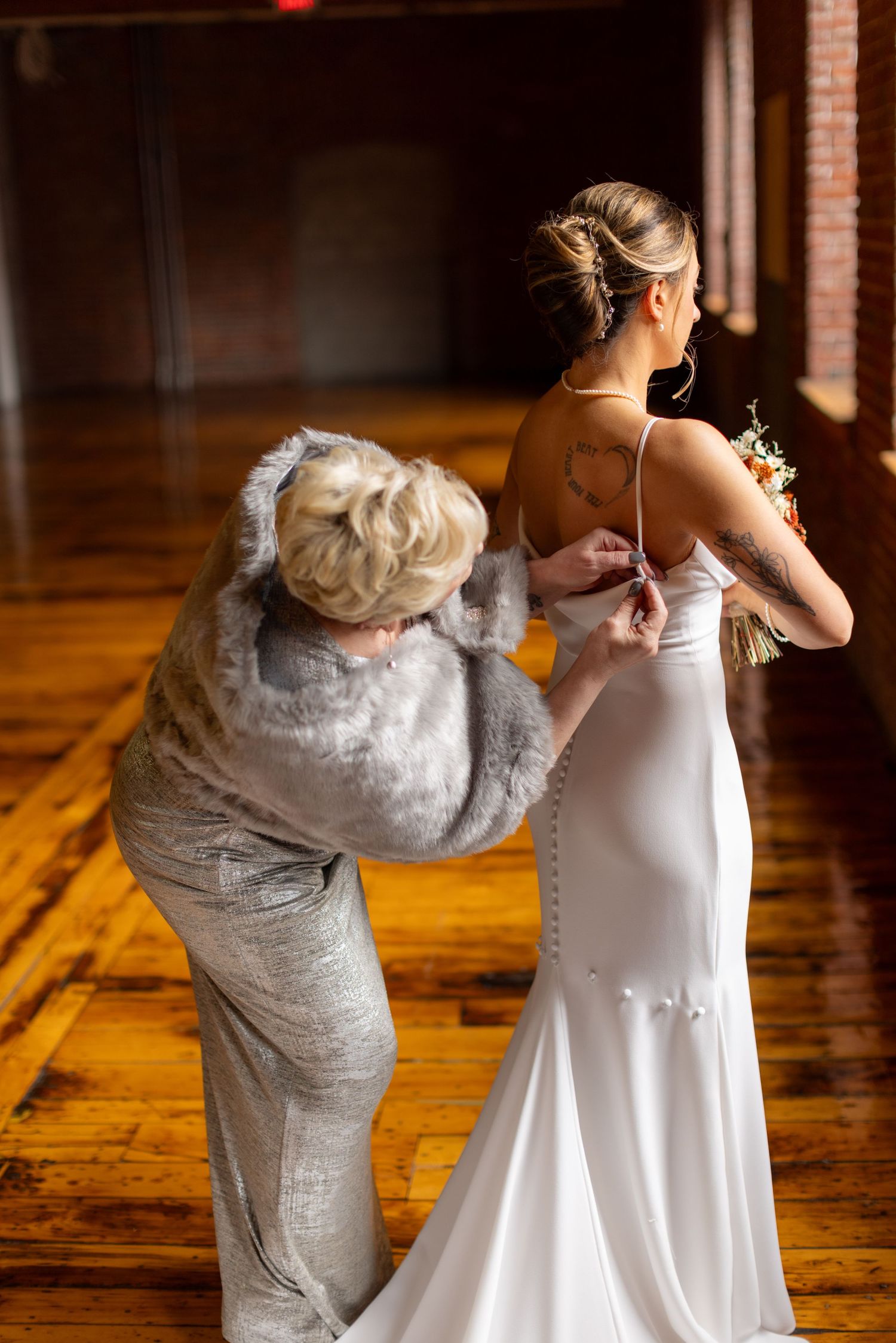 Final wedding dress adjustments being made on hardwood floor.