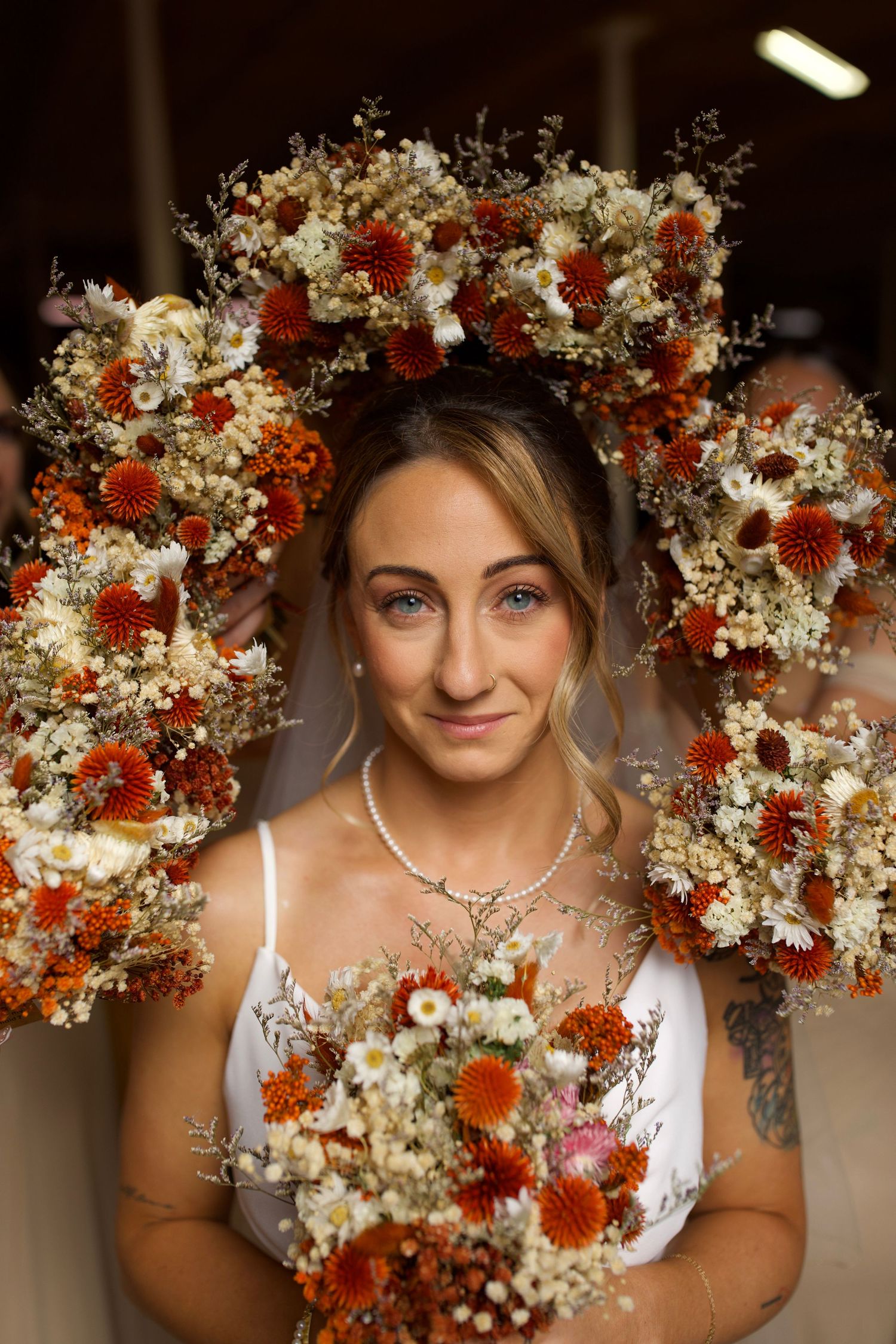 Stunning floral crown with red and white flowers framing bridal portrait.