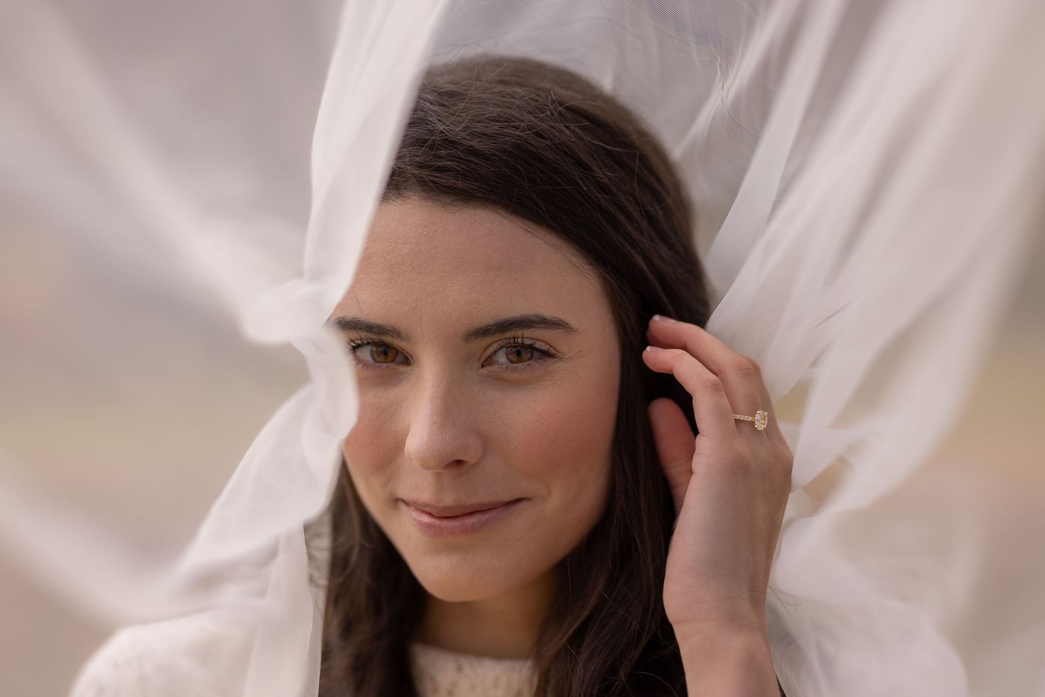 Close-up portrait with white veil and elegant jewelry.