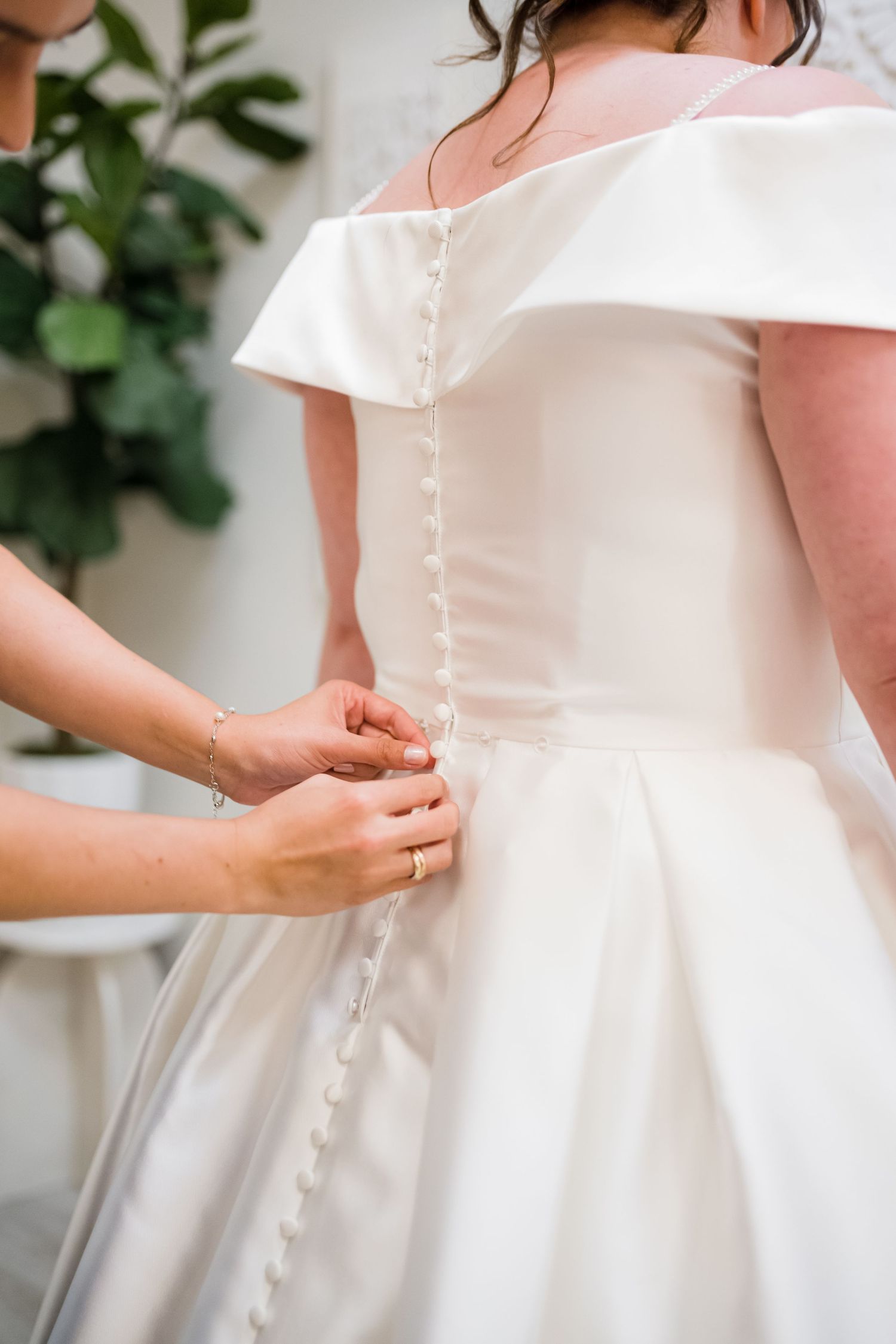 Close-up of delicate button details on back of white wedding dress.