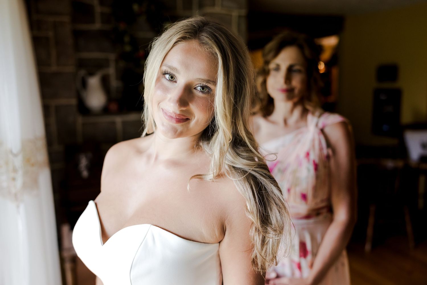 Professional wedding photographer captures intimate moments of bride getting ready with bridesmaids in natural light.