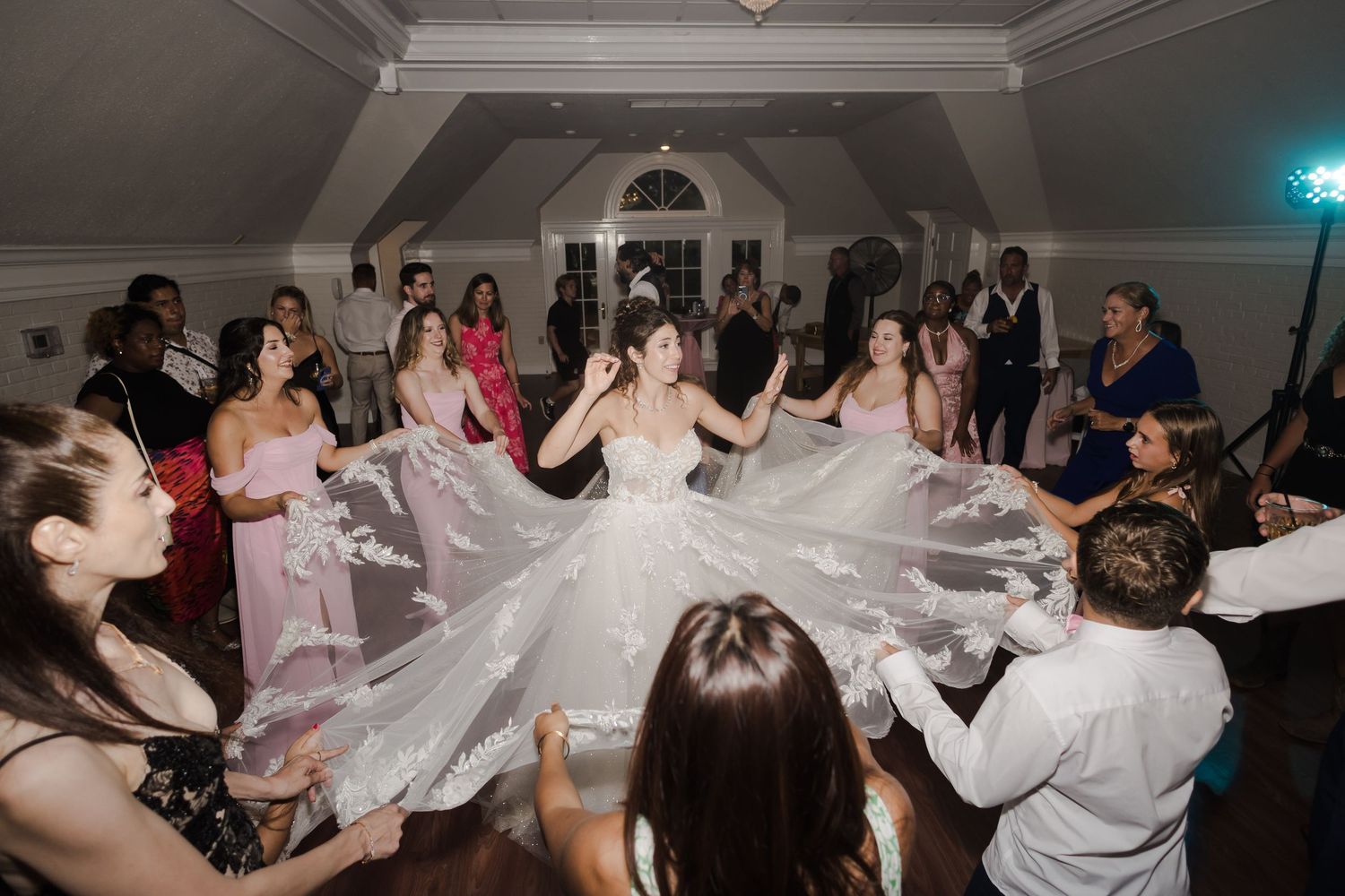 Wedding guests dance together on the dance floor during an evening celebration at a wedding reception.