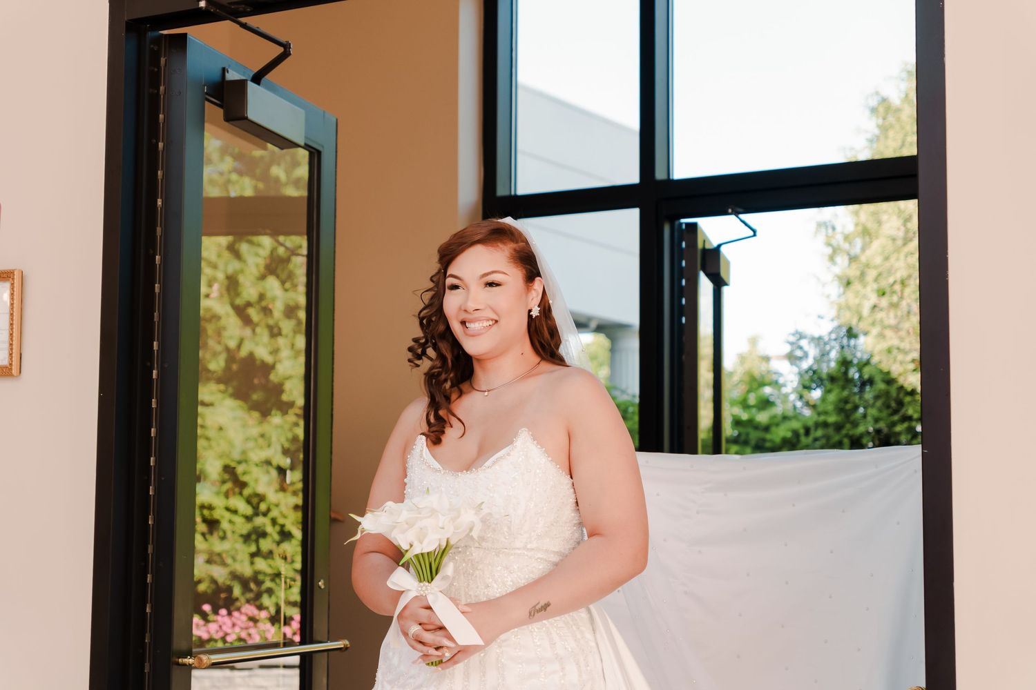 Bride getting ready in a bridal room with natural light streaming through windows.