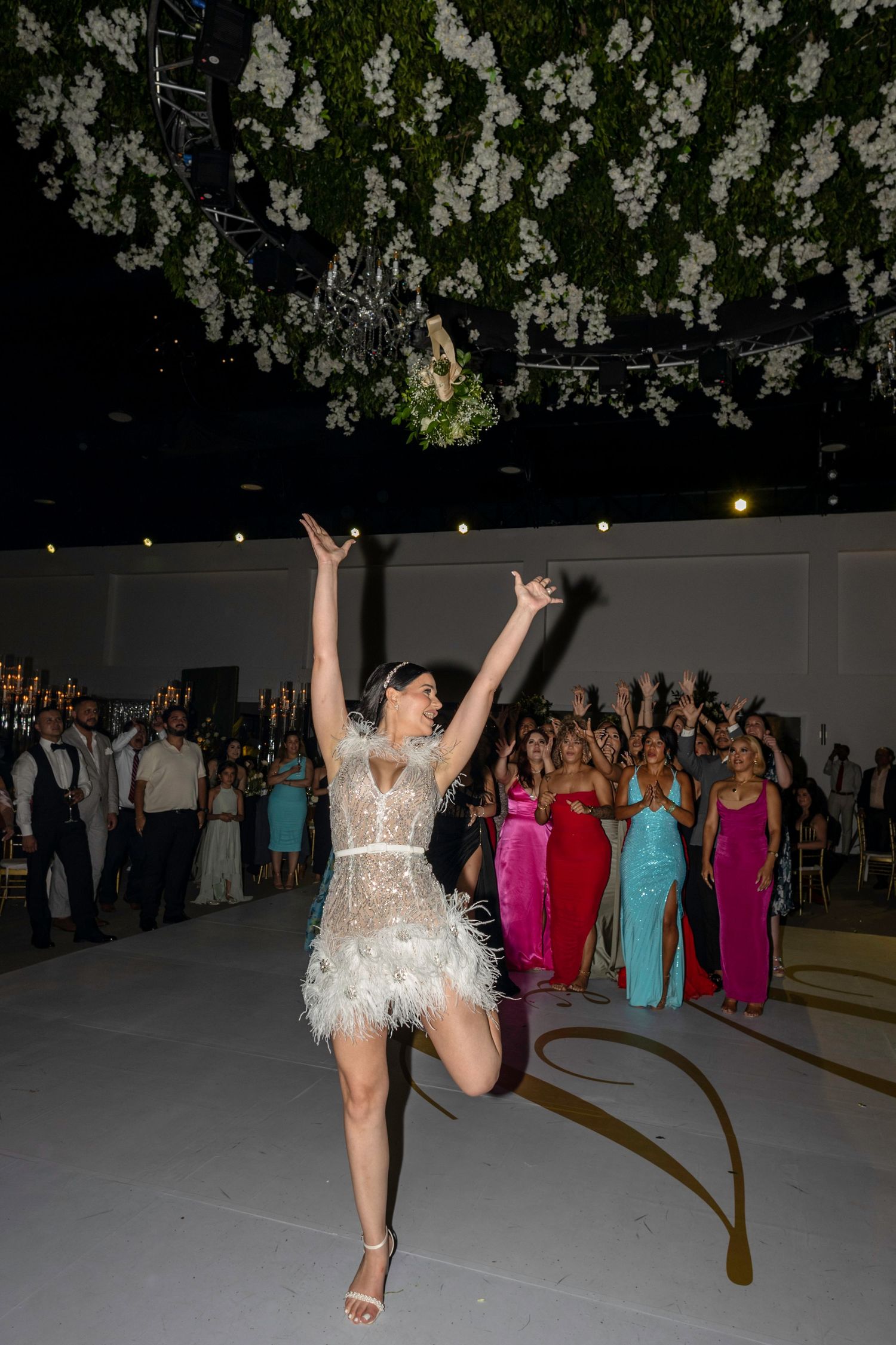Wedding reception dance floor with floral ceiling decorations and colorful party lights.