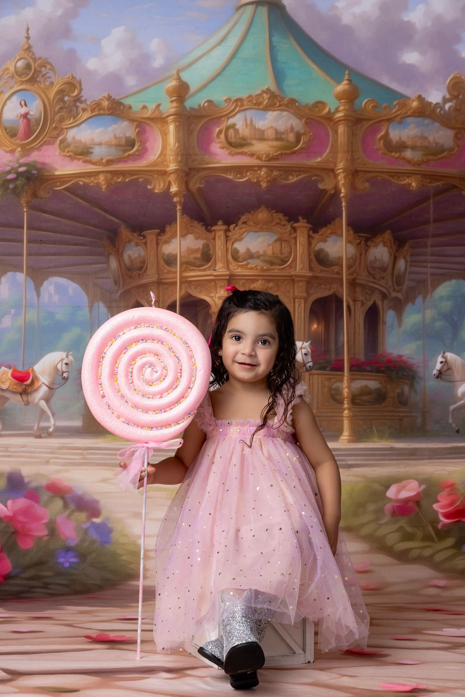 A whimsical carousel-themed photo setup with pink decor and a giant lollipop prop.