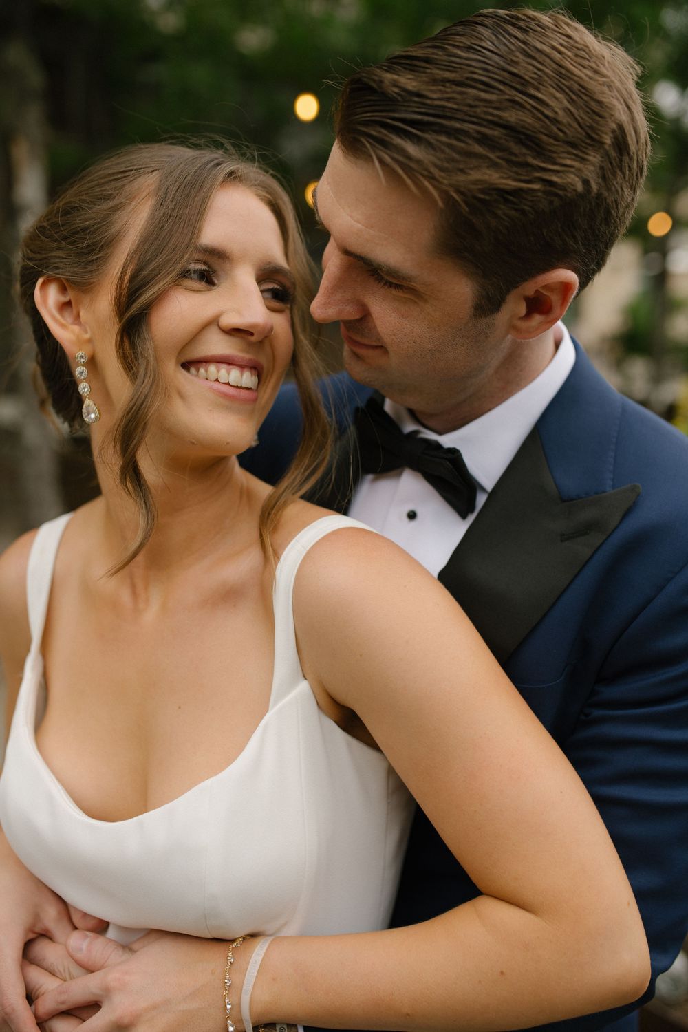 Romantic newlyweds pose lovingly together outside during wedding portraits at dusk.