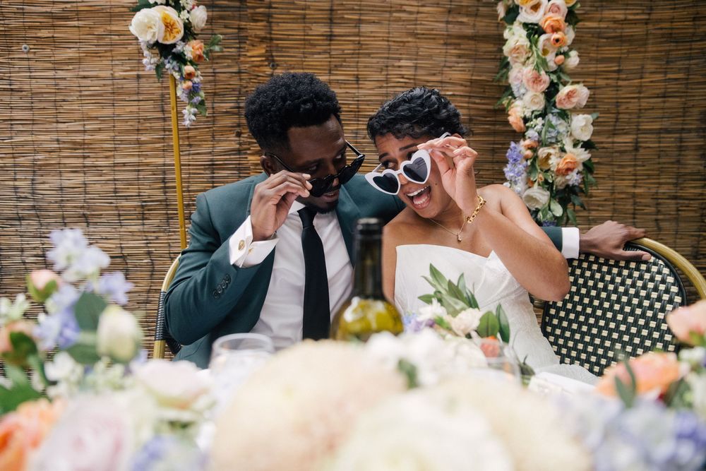 An elegant wedding venue decorated with white and peach roses and greenery displays arranged along bamboo wall backdrops.