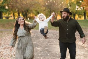 A playful family moment captured while swinging their child in a park.