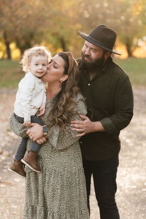 A tender family moment captured outdoors in autumn with a leopard print dress and black hat.