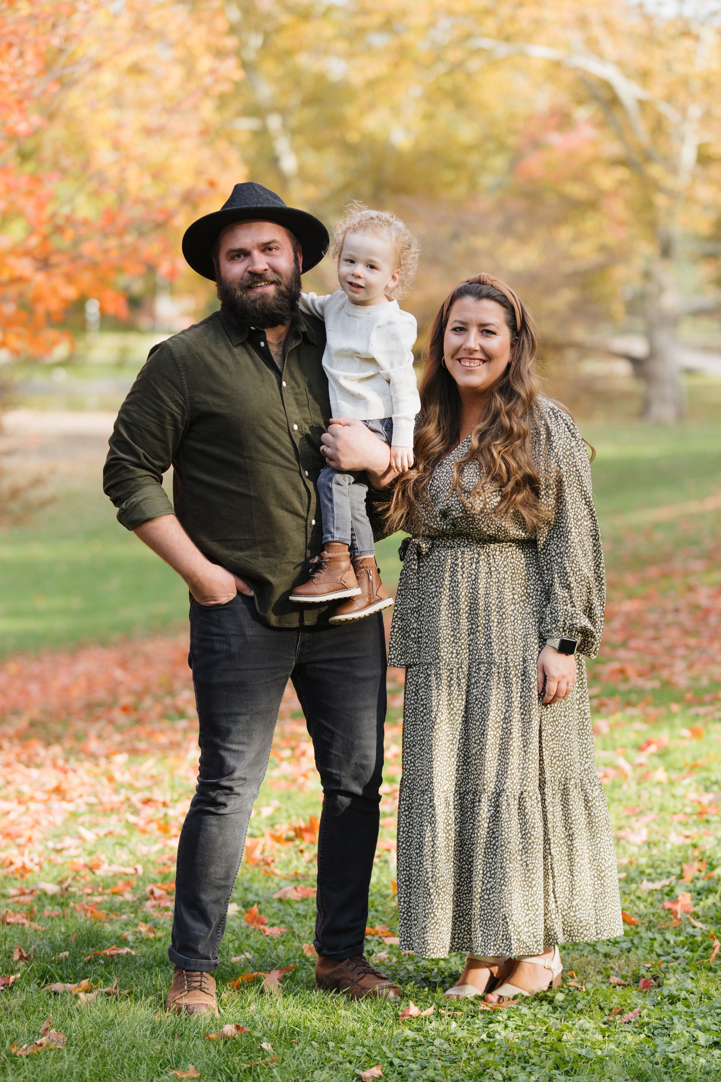 A family portrait in a park with beautiful fall foliage.