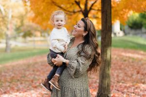 A tender moment between parent and child among autumn leaves.