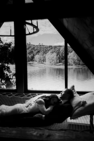 Serene lakeside view through cabin windows with figures silhouetted against the water.