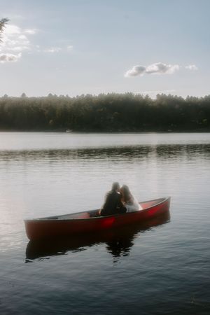 Silhouette of a red canoe gliding across a serene lake at dusk.