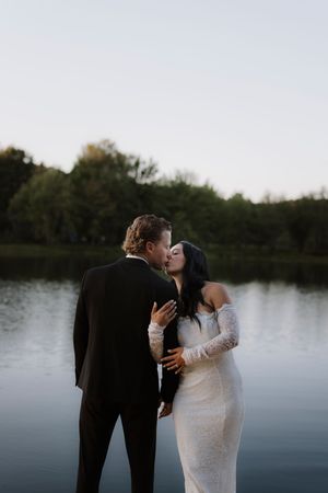 A romantic lakeside moment captured against a tranquil water backdrop.