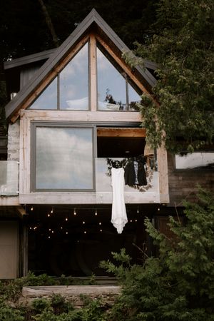 Modern A-frame wedding venue with large windows and string lights at dusk.