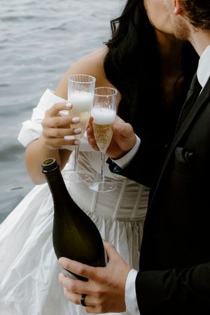 Newlyweds toast with champagne glasses while celebrating on a boat.