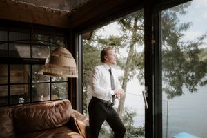 Panoramic view of a cozy cabin interior with leather seating and windows facing a lake.