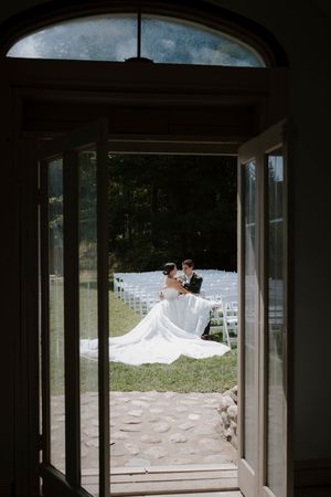 A wedding dress train flows elegantly through an open doorway onto a stone patio.