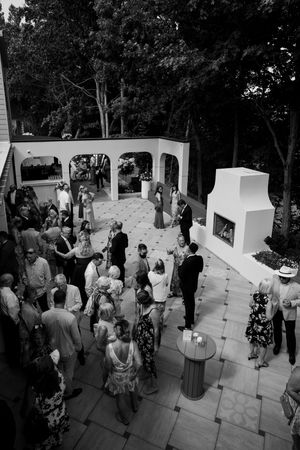 Wedding guests gather on an outdoor patio during a ceremony.