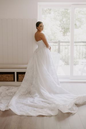 Elegant white wedding gown with long cathedral train displayed in bright indoor setting.