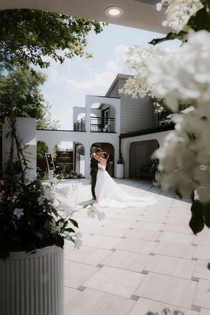 Modern white courtyard with architectural details and blooming flowers in the foreground.