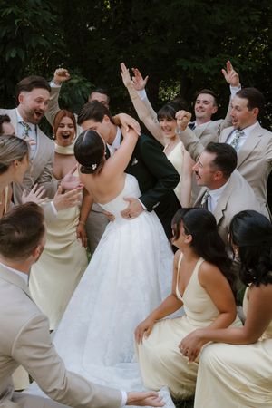 Wedding party celebrating with raised hands and joyful expressions.