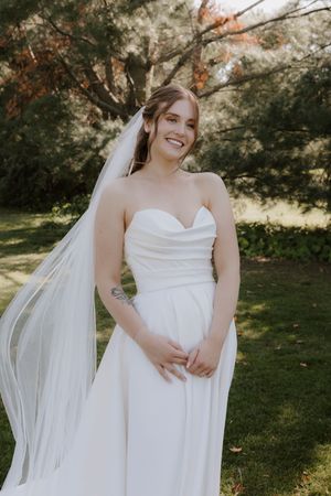 A bride in a flowing white dress twirls in a sunlit garden setting.