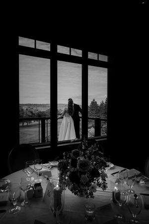Wedding reception table settings silhouetted against large windows with panoramic views.