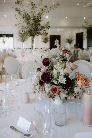 Elegant wedding reception tables decorated with burgundy and blush floral centerpieces.