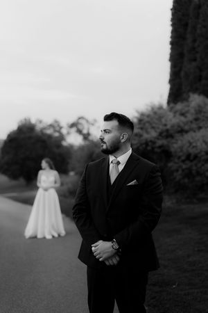 Groom in black suit poses for portraits on golf course grounds.