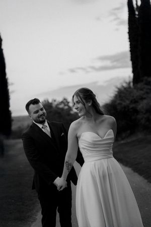 Couple shares playful moment during sunset wedding photoshoot on golf course.