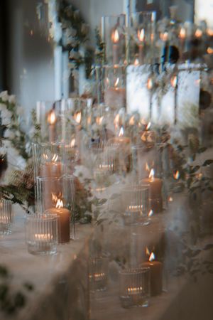 Romantic candlelit wedding reception tables with glass votives creating ambient lighting.