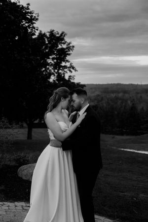Dramatic black and white wedding portraits captured against a scenic hilltop backdrop.