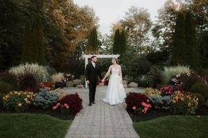 A wedding ceremony setup in a garden with stone pathways and colorful flower beds.