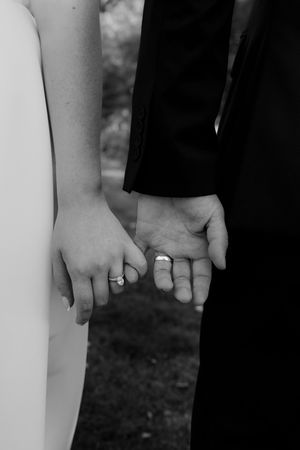 Close-up of newlyweds holding hands showing their wedding rings.