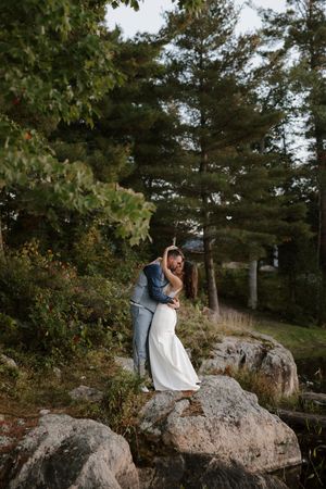 Intimate wedding portrait session on natural rock formation surrounded by pine trees.