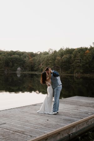 Romantic couple moment on wooden dock overlooking tranquil lake at sunset.