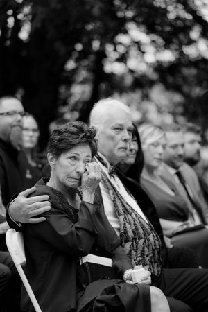 Wedding guests show emotional reactions during ceremony while holding white candles.