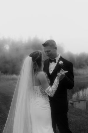 Black and white portrait of newlyweds sharing an intimate moment outdoors.