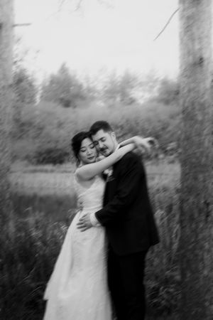 Artistic black and white wedding portrait showing intimate moments in a forest setting.