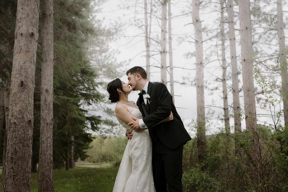 A romantic wedding couple shares a tender moment on a swing in a misty forest setting.