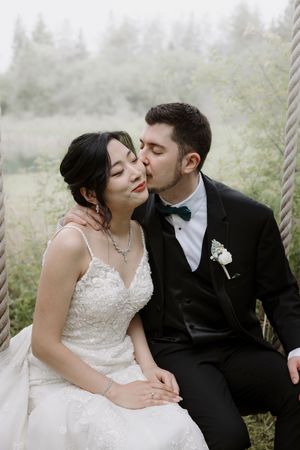 Intimate wedding portrait captured on a swing in a dreamy woodland setting.