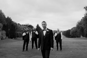 Wedding party silhouettes walking across expansive green lawn.