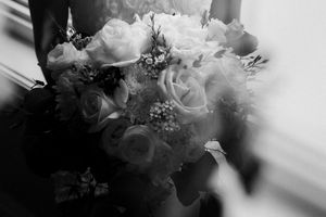 Close up of a white bridal bouquet with roses and delicate florals in monochromatic tones.
